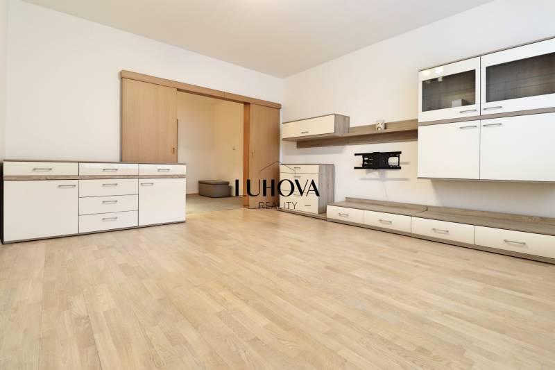 Living room in a 3-room apartment with white furniture and a wooden decor floor.