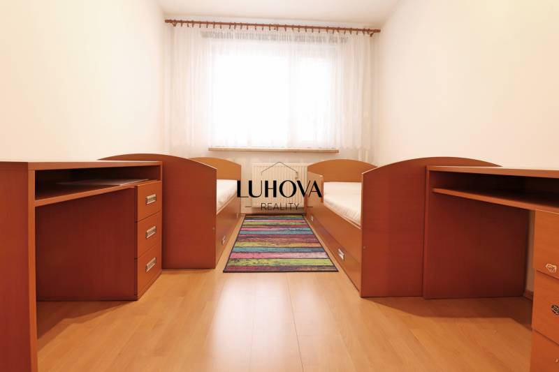 Children's room with two beds, desks, and a wooden decor floor.