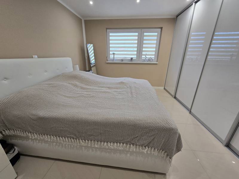 A bedroom in a family house with a large bed, a wardrobe, and white blinds.