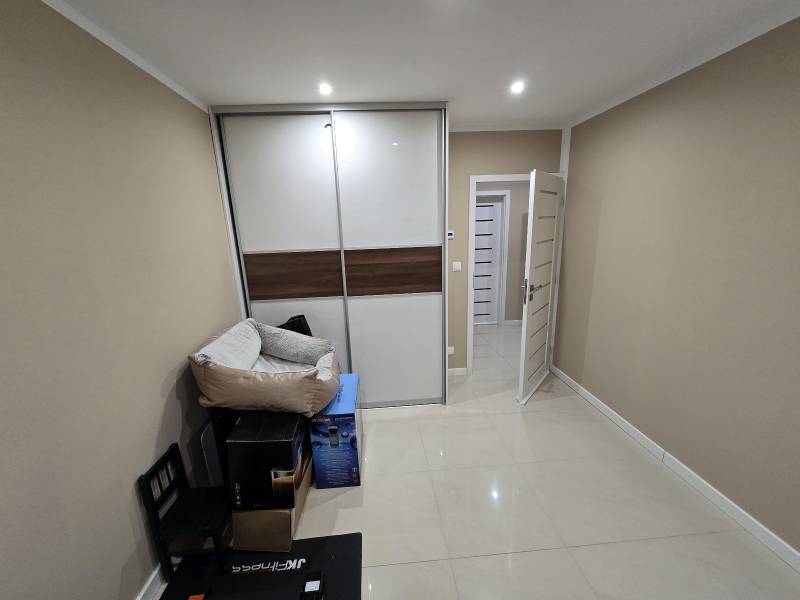 A room in a family house with tiles, a wardrobe, and packaged furniture.