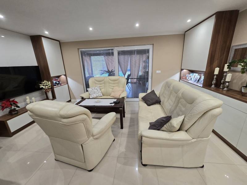 Open living room with cream seating, decorative candlesticks, and shelves in a family house.