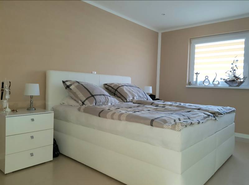 Bright bedroom with a bed, nightstand, and decorations in a family house.