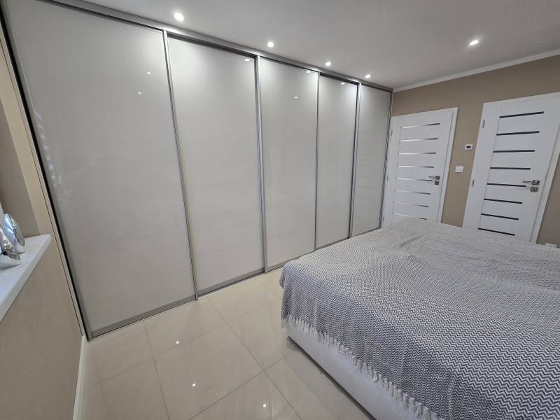 Bedroom in a family house with a large built-in wardrobe and tiled floor.