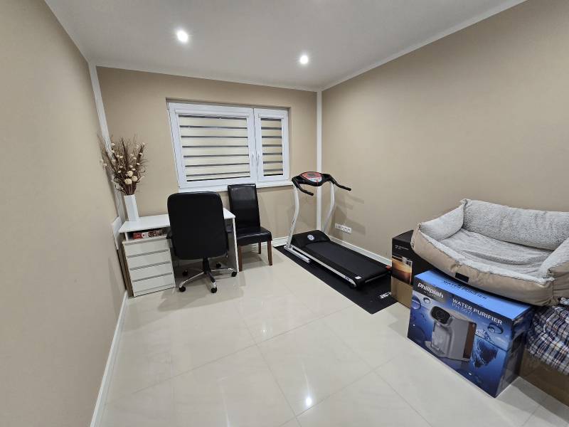 A study in a family house with a writing desk, a treadmill, and a clean white floor.
