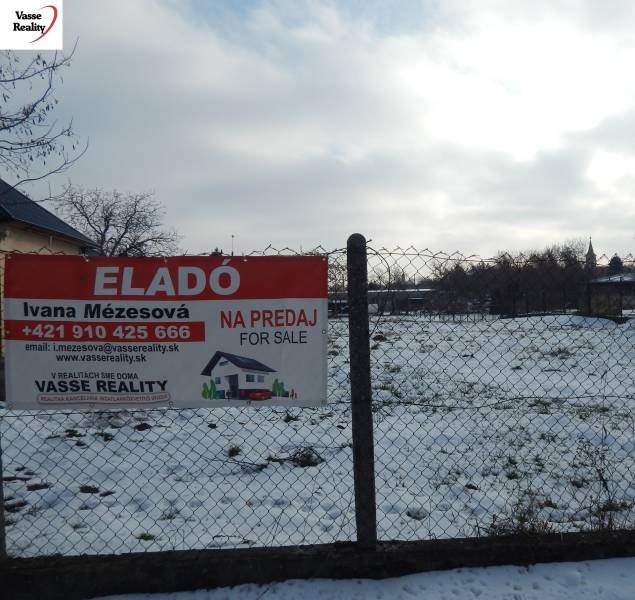 Snow-covered plot for sale in Čalovec, suitable for housing, behind a fence with a sign.