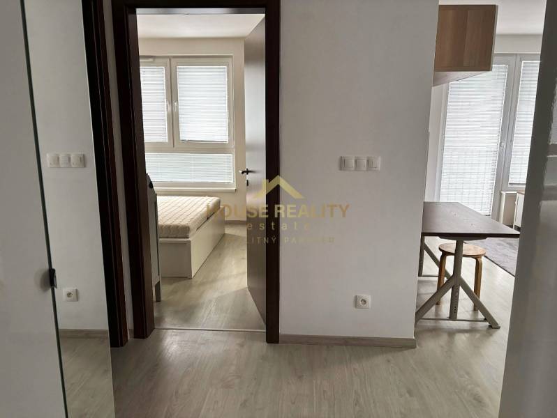 Interior of a 2-room apartment with a wooden decor floor and a view of the bedroom.