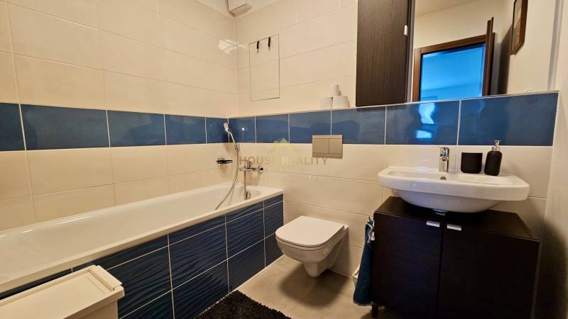 A bathroom in a 2-room apartment with a bathtub and blue-white tiles.