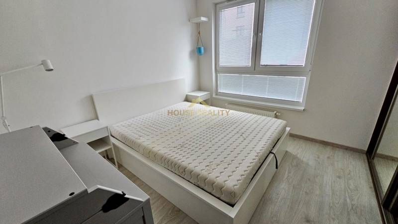 A bright bedroom with a bed and wood-decor flooring in a two-room apartment.