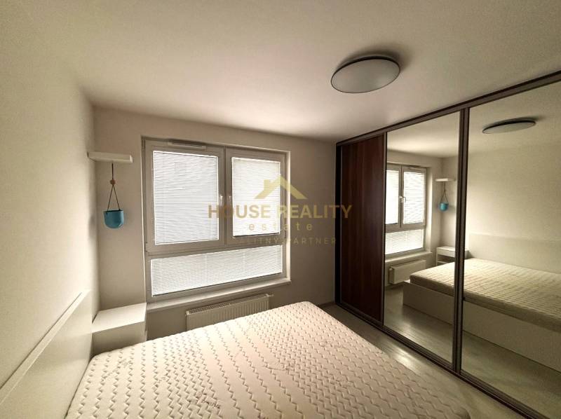 A bedroom in a 2-room apartment with a built-in wardrobe and adjustable blinds on the window.