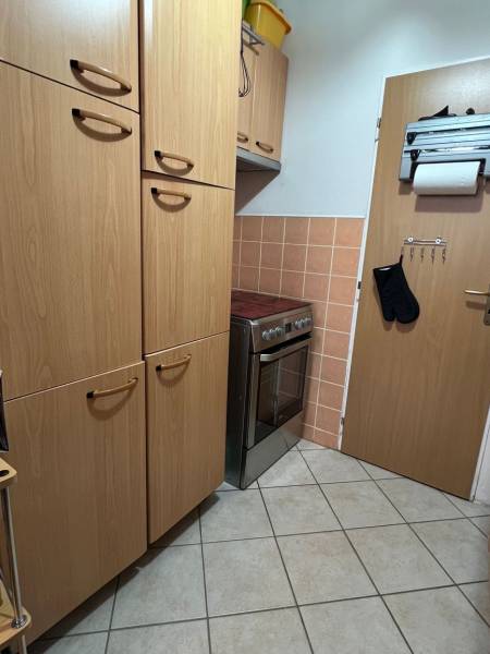 A kitchen with nice cabinets and a stove in a studio apartment, flooring with a wood decor.