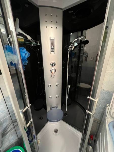 Hydromassage shower cabin in a studio apartment with functional shower jets and storage space.