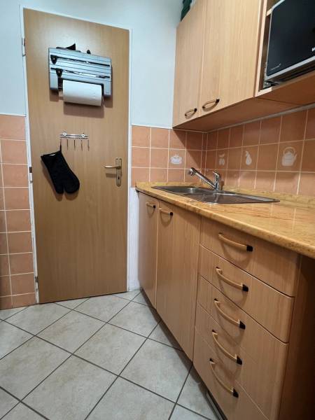 A kitchen unit with a wooden decor and ceramic tiles in a studio apartment.
