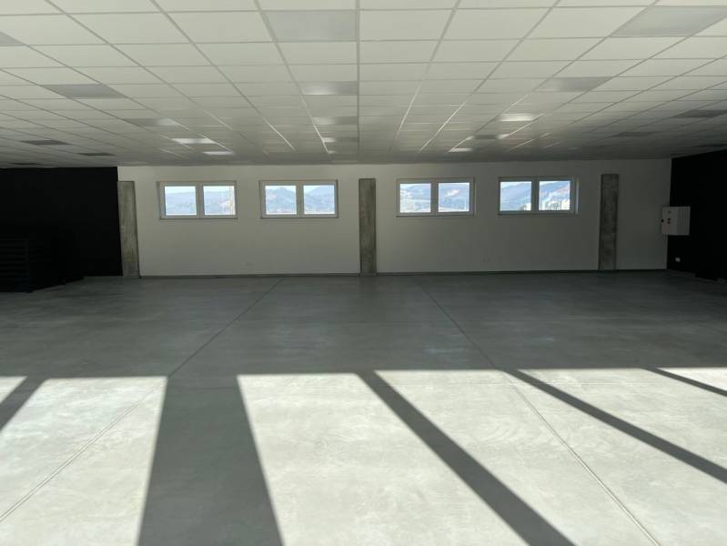 Spacious commercial spaces with large windows and concrete floors, illuminated by natural light.