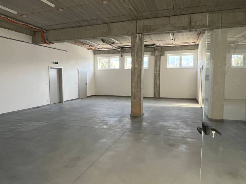 Commercial spaces with large windows and concrete flooring, neutral walls and a pillar.