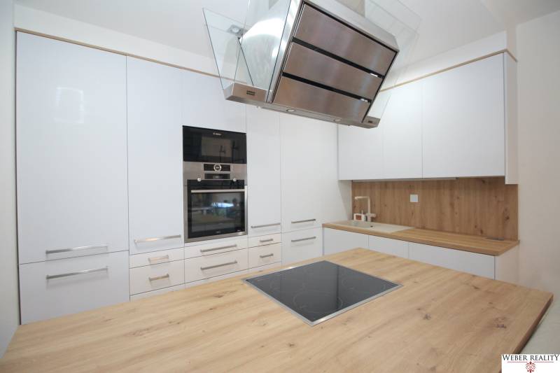 A kitchen in a 2-room apartment with white cabinets and a wooden-patterned floor.