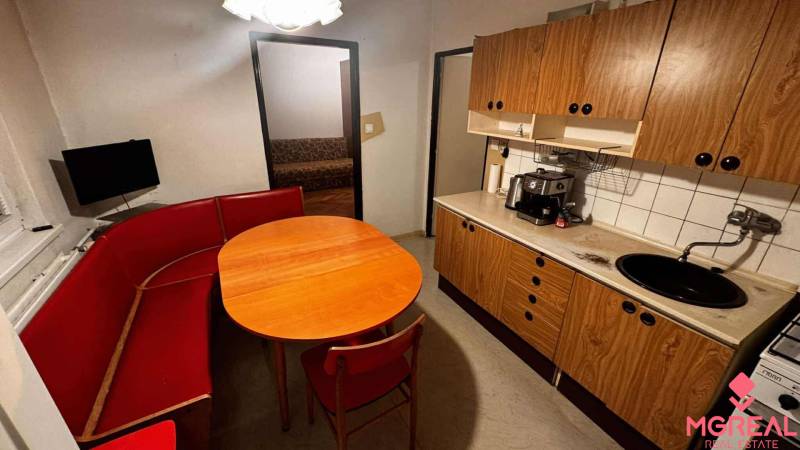 A kitchen in a 2-room apartment with a red bench and a kitchen unit with a wooden decor.
