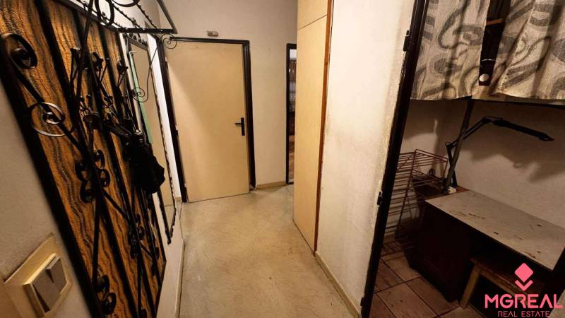 A narrow hallway in a 2-room apartment with a coat rack and built-in wardrobes.