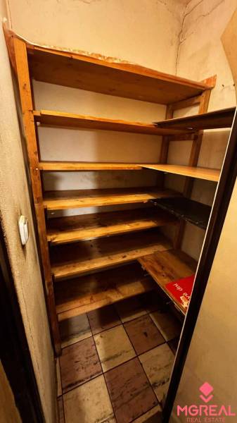 Wooden shelves in the pantry of a 2-room apartment with tiles.