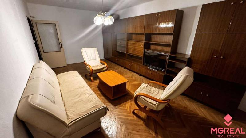Living room with a sofa, armchairs, furniture, and a wooden decor floor in a two-room apartment.