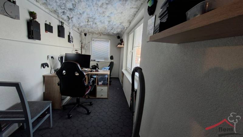 A workspace in a family house with gaming consoles on a light wall.