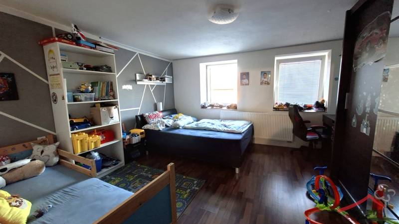 Children's room in a family house with beds, toys, and a wooden decor floor.