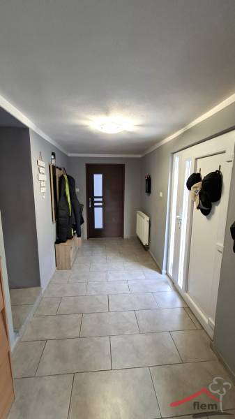 A hallway in a family house with coat racks, a radiator, and tiled flooring.