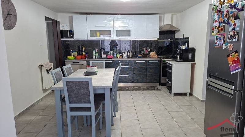 A kitchen in a family house with a dining table, kitchen unit, and appliances.