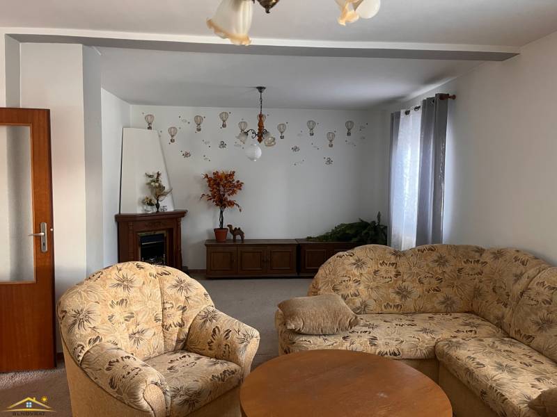 Living room in a family house, with a floral armchair, ornaments, and a fireplace.