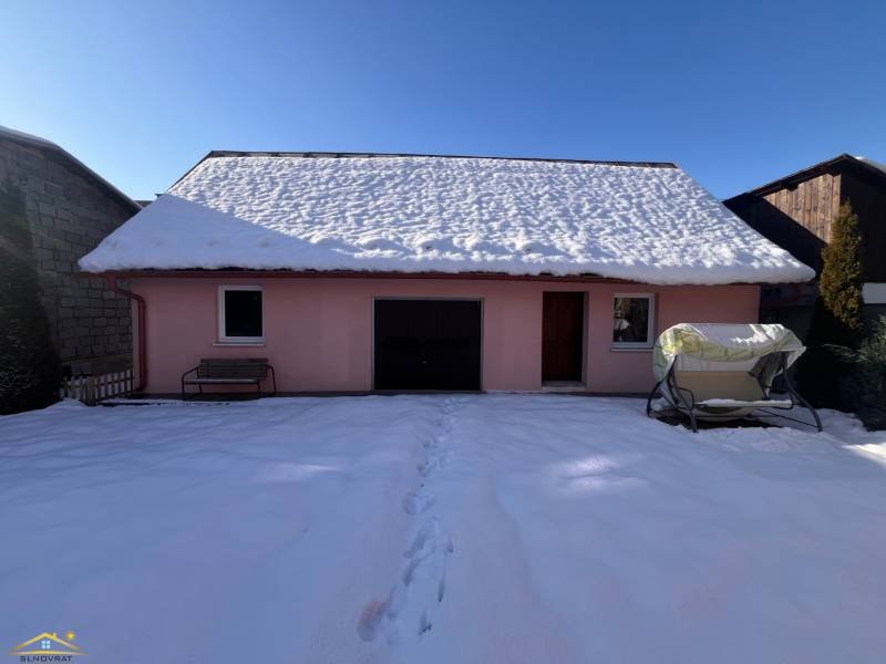 A family house in Stará Bystrica covered with snow, seating at the entrance, sunny winter day.