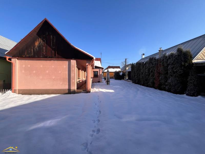 A family house in a snowy garden in Stará Bystrica with a blue sky.