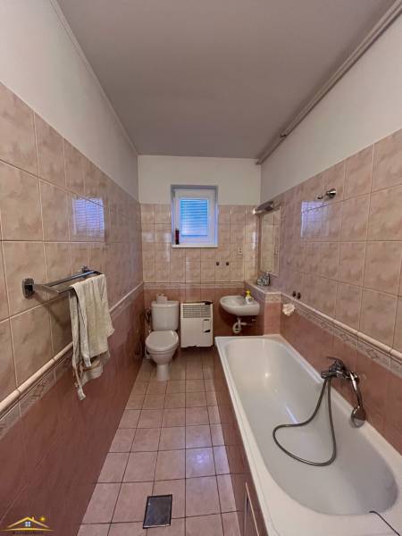 Bathroom with a bathtub and toilet in a family house, with tiles and ceramic flooring.
