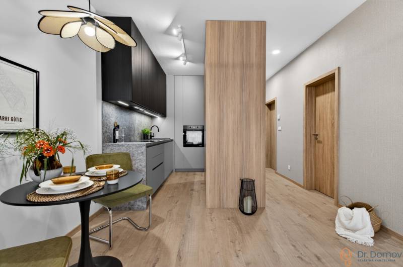 A kitchen in a 2-room apartment with a wooden decor floor, a dining table, and interesting lighting.