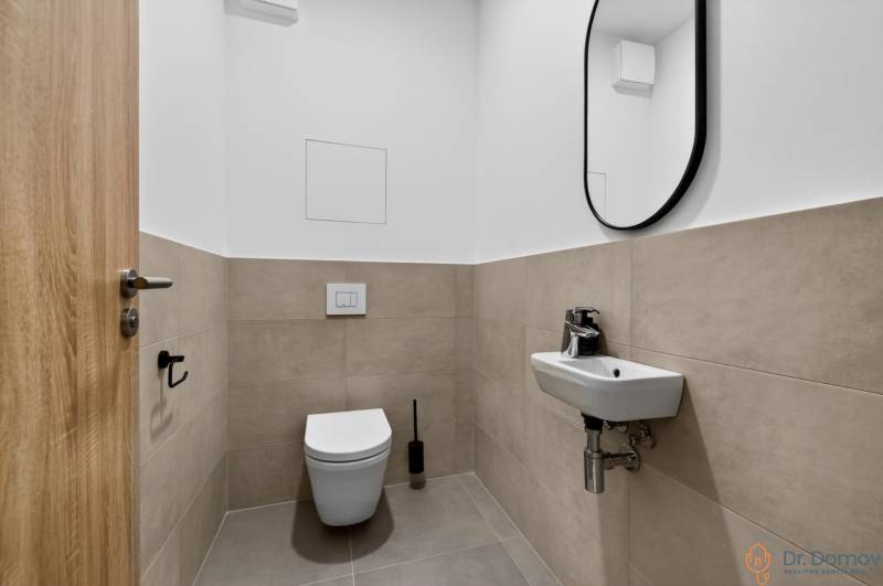 A toilet with a sink and mirror in a 2-room apartment. Beige and white tiles.