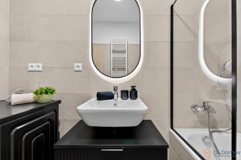 A bathroom in a 2-room apartment with a sink, mirror, and bathtub, simple elegant design.