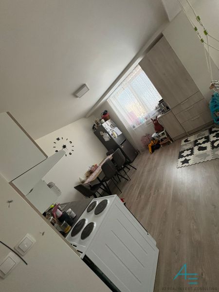 A kitchen in a 2-room apartment with a dining table and a floor with a wood decor.