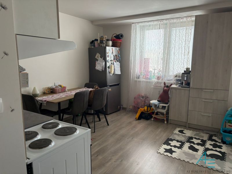 A kitchen in a 2-room apartment with a wooden decor floor and a dining table.