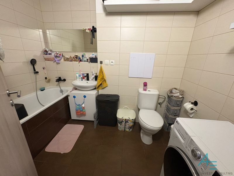Bathroom in a 2-room apartment with a shower, toilet, and washing machine.