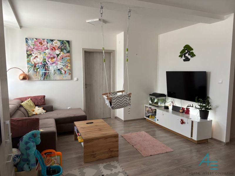 Living room in a two-room apartment with a play corner and a floor with a wooden decor.