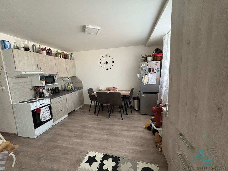 A kitchen in a 2-room apartment with a dining table, floor with wood decor.