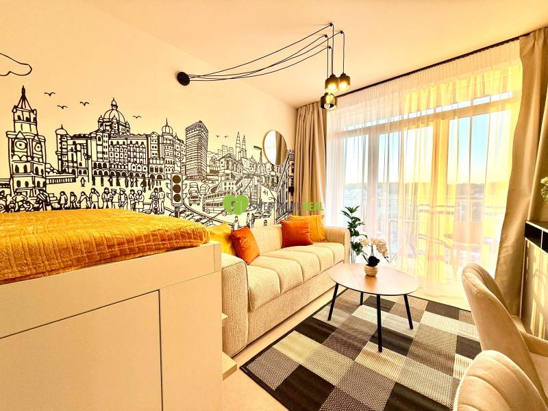 A stylish living space in a studio apartment with a wall mural and a balcony.