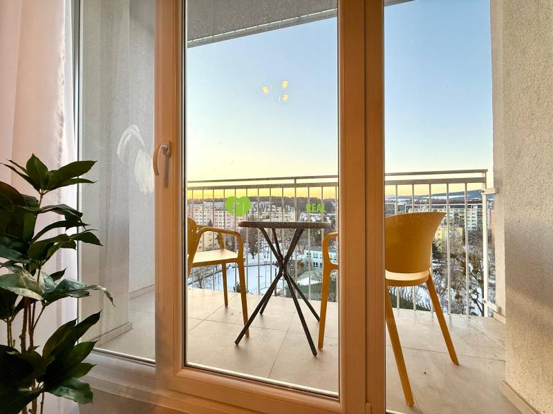 French window with a view of the balcony with chairs in a studio apartment.