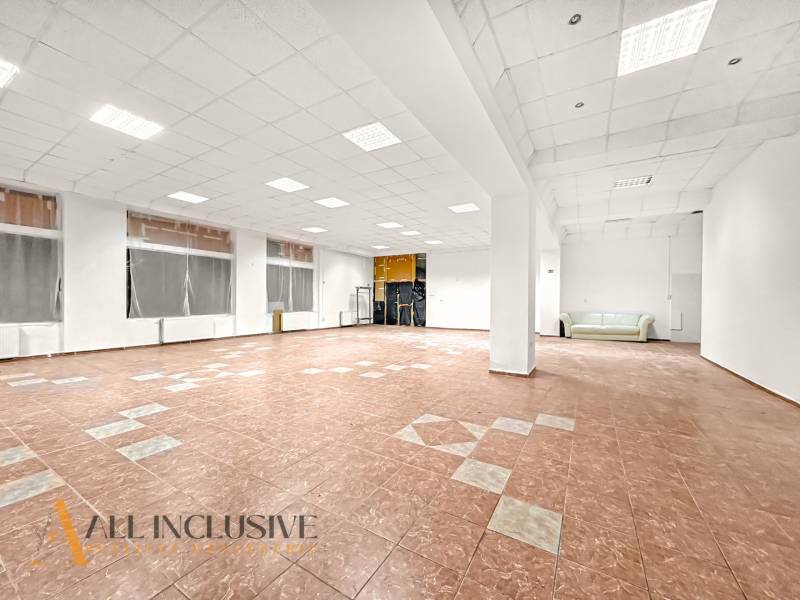 Spacious commercial spaces with large windows, gray ceiling, and a sofa.