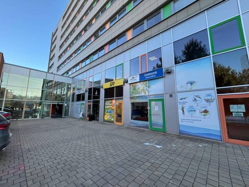 The facade of the building with glass offices in Poprad on a paved parking lot.