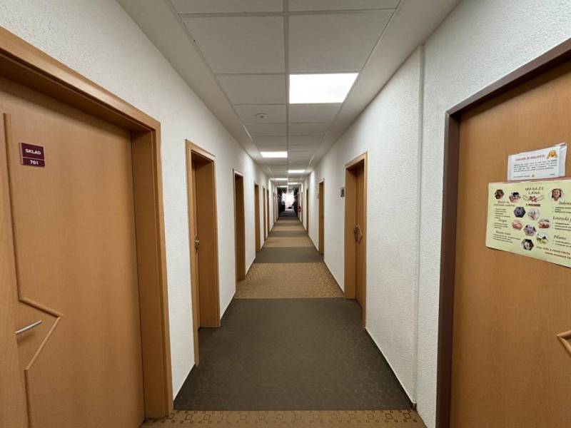 A narrow corridor with brown doors leading to various offices.