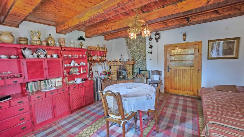 The interior of a family house with a wooden ceiling, a red cabinet, and a dining table.