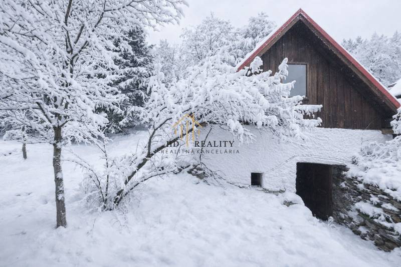 A snow-covered family house in the village of Stará Huta on Stará Huta 84 street surrounded by trees.