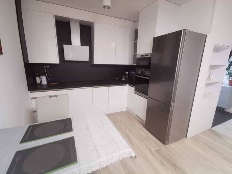 A kitchen in a 2-room apartment with a wooden decor floor and modern equipment.