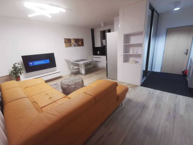 Living room in a two-room apartment with a yellow sofa and a wooden decor floor.