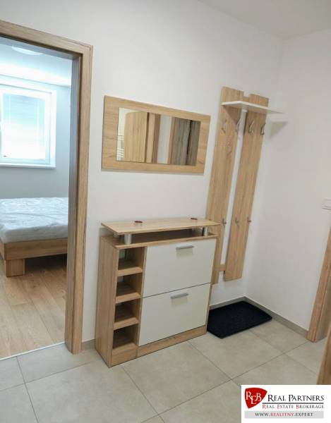 Hallway in a 3-room apartment with a coat rack, mirror, and cabinet, leading to the bedroom.