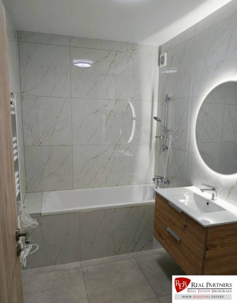 A bathroom with a bathtub, sink, and illuminated mirror in a 3-room apartment.